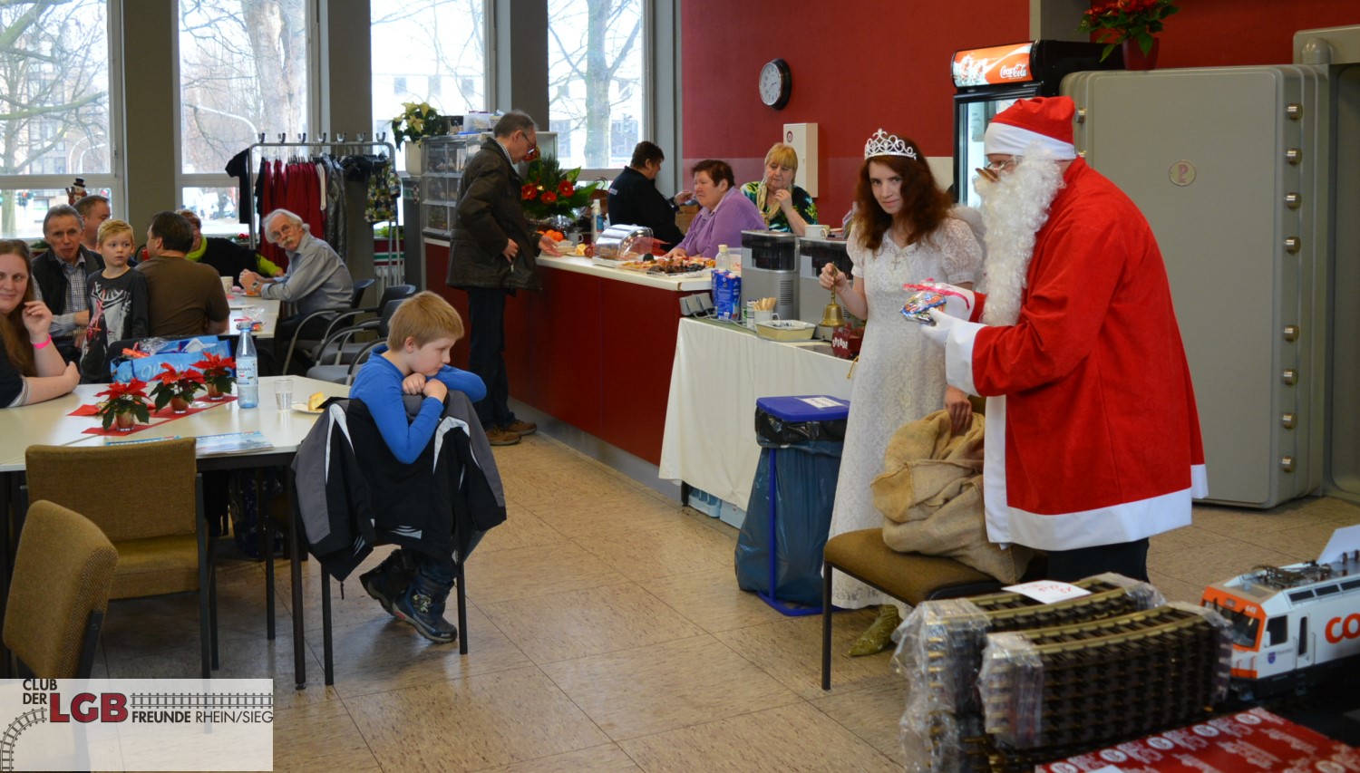 r uns erstaunlich uns sehr erfreulich war die hohe Anzahl der Kinder, die von Ihren Eltern begleitet sich an den Zgen erfreuten, aber sicherlich innerlich sehr gespannt auf den Weihnachtsmann unseres Clubs warteten.  Dieser hatte es dann auch am Nachmittag geschafft, sich durch den Kamin zu qulen und erschien wie immer mit groem Gepolter und Gelute, begleitet von einem wunderschnen Engel, um sich nach anwesenden Kindern zu erkundigen. Schlagartig war Ruhe, die wildesten Kerle wurden weich wie Butter und erst scheu, dann aber immer mutiger, oft aber auch nur unter Schutz und Begleitung des Papas oder der Mama, nahmen die kleinen Eisenbahnfans die Geschenke des Weihnachtsmannes an und lauschten ehrfurchtsvoll seinen Worten.   In diesem Jahr wurden dann auch einige Erwachsene vom Weihnachtsmann bedacht. 